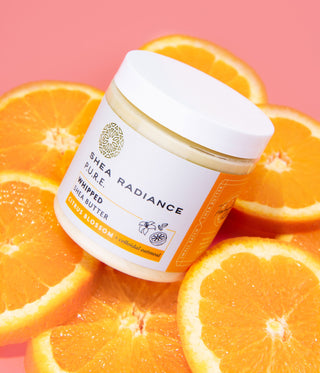 Shea Radiance Whipped Shea Butter tub on a table covered with oats