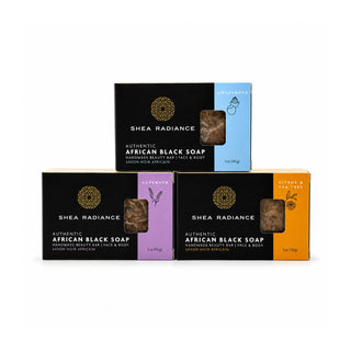 Three Shea Radiance Authentic African Black Soap bars in their retail packaging, arranged in a triangular stack on a white background. The top box is black and light blue (Saffron), and the bottom two boxes are black with purple (Lavender) and orange (Citrus & Tea Tree) accents.