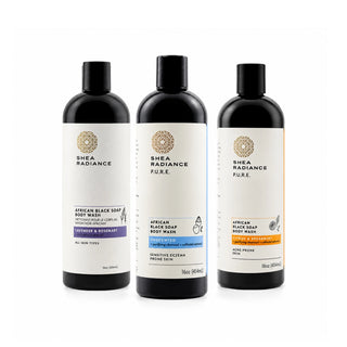 Three Shea Radiance Pure African Black Soap Body Wash bottles in black plastic with white labels, shown side by side on a white background. The labels feature gold circular logos and color-coded accents in purple, blue, and orange.