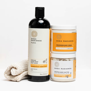 Shea Radiance citrus body care products including a body wash bottle, nourishing cream jar, shipped butter jar, and sisal cloth on a white background