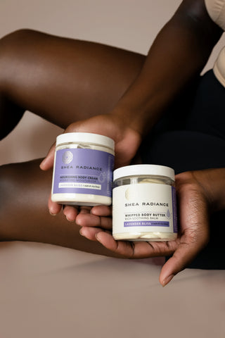 Two containers of Shea Radiance body products held by a person against a neutral background