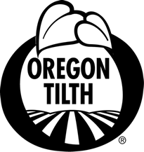 A black circular logo with the words 'OREGON TILTH' in bold black letters, featuring a stylized wheat stalk above and field rows below, on a white background.