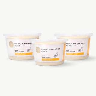 Three containers of orange & clove large Shea Radiance raw shea butter on a white background