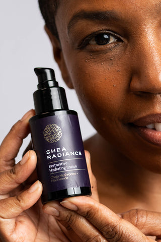 Woman holding a Shea Radiance skincare bottle against a neutral background