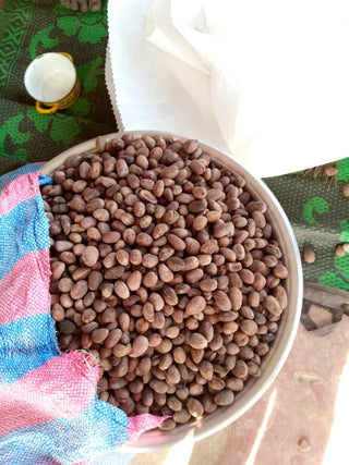 White bowl filled with brown seeds on a colorful fabric background